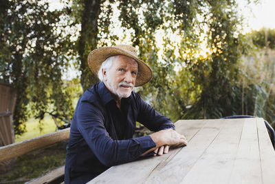 Smiling senior man wearing hat sitting at wooden table