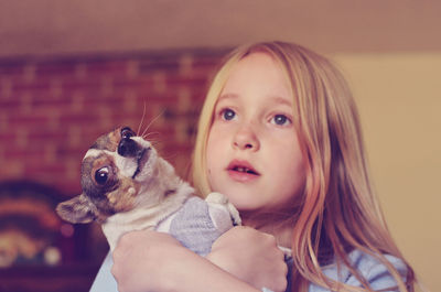 Blond girl holding chihuahua dog yawing at home