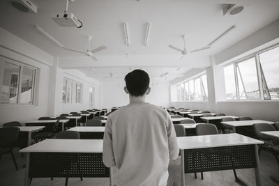 Rear view of man sitting table in classroom