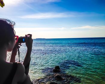 Man photographing sea against sky