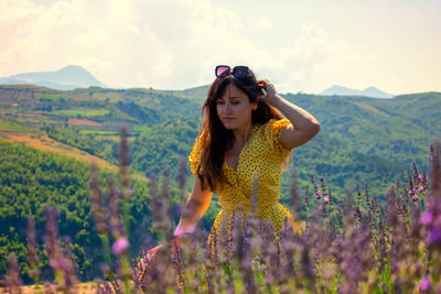 Beautiful young woman standing on field against mountain