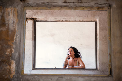 Portrait of smiling young woman against window