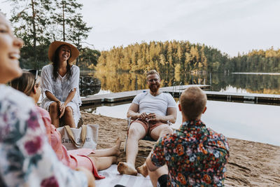 Group of people sitting on shore against trees