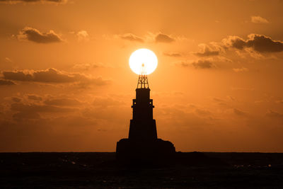 Silhouette of a lighthouse against sun