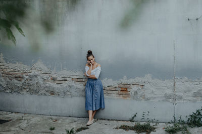 Portrait of smiling young woman standing against wall