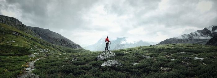 Rear view of man standing on mountain against sky