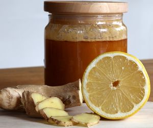 Close-up of honey in jar with ginger and halved lemon on table
