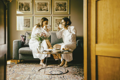 Couple in bathrobes drinking coffee while enjoying breakfast at hotel