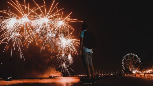 Man looking at firework display over river in city