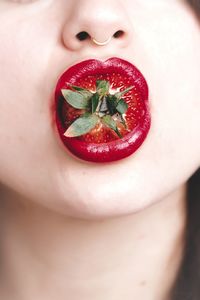 Cropped image of woman with red lipstick eating strawberry