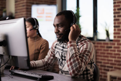 Customer service representative with colleague working at desk in office