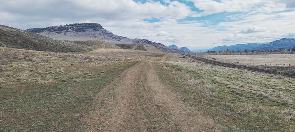 Dirt road on landscape against sky