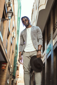 Low angle view of young man standing against buildings in city