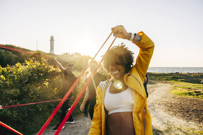 Determined woman pulling resistance band during group training at beach