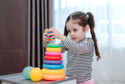 Girl playing with multi colored toys at home