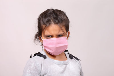 Portrait of girl wearing flu mask against white background