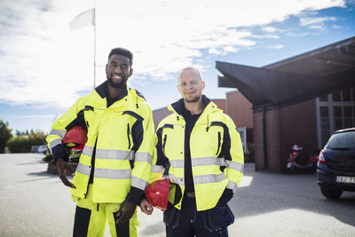 Portrait of confident auto mechanic student and teacher wearing reflective clothing outdoors