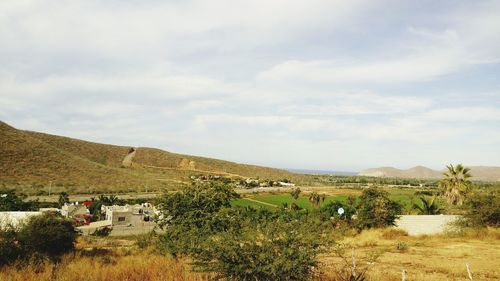 Scenic view of grassy field against cloudy sky