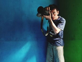Portrait of young woman standing against blue wall