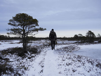 Rear view of man hiking on snow during sunset