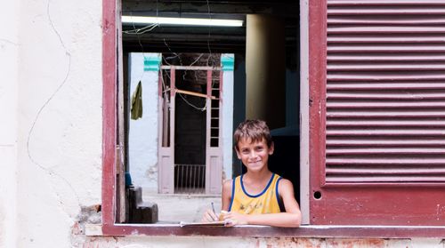 Portrait of smiling boy sitting on window