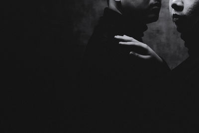Side view of woman standing against black background