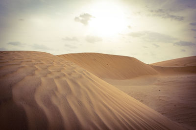 Sand dunes in desert against sky