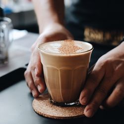 Cropped hands of person holding coffee at cafe