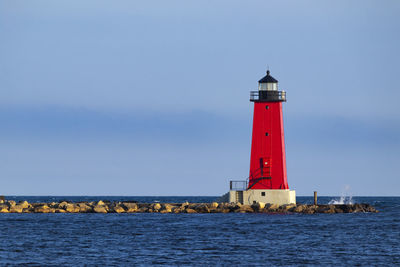 Lighthouse by sea against sky