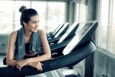 Smiling woman standing on treadmill in gym