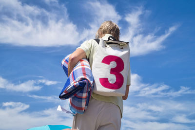 Low angle view of man with backpack against sky