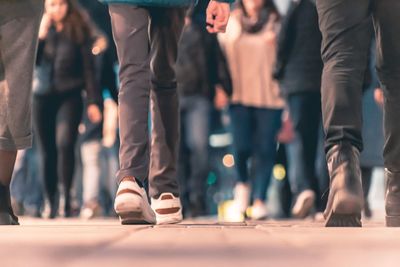 Low section of people walking on street in city