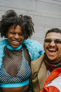 Cheerful hipster woman and gay man against wall