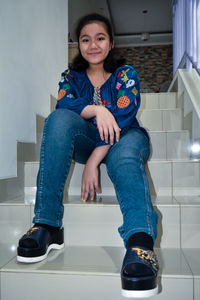 Portrait of a smiling young woman sitting on tiled floor