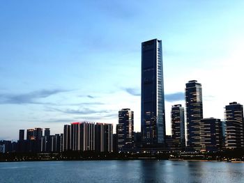 Sea by modern buildings against sky in city