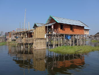 Wooden house by lake against sky