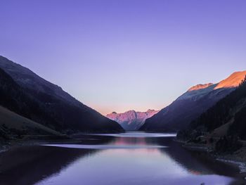 Scenic view of lake and mountains against clear blue sky