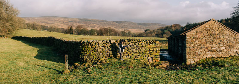 Scenic view of field by houses against sky