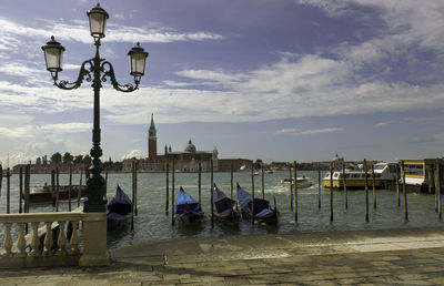 Venice, gondolas or gondole, street light and san giorgio maggiore church landmark on background.