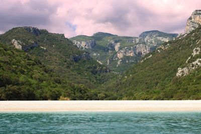 Scenic view of sea and mountains against sky