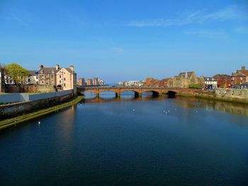 Arch bridge over river against buildings in city