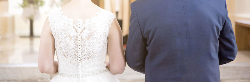 Midsection of bride holding wedding dress