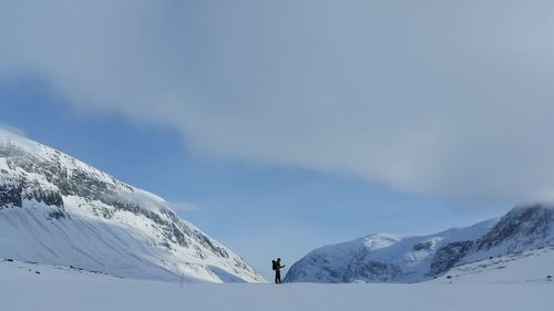 Scenic view of hiker in snowcapped mountains of kungsleden against sky