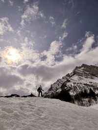 Man standing on snowcapped mountain against sky