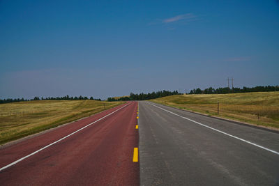 Empty road amidst landscape against clear sky
