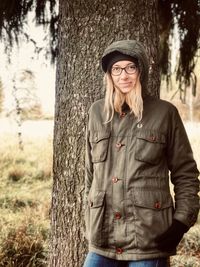 Portrait of man standing by tree trunk