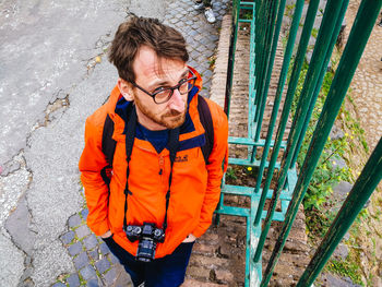 High angle portrait of man standing against orange wall