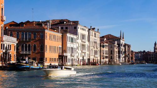 Buildings by sea against blue sky