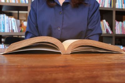 Midsection of man reading book on table
