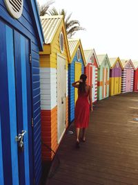 Rear view of woman walking by colorful beach huts